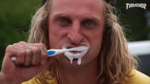 A Man Is Brushing His Teeth With A Thrasher Logo In The Background GIF