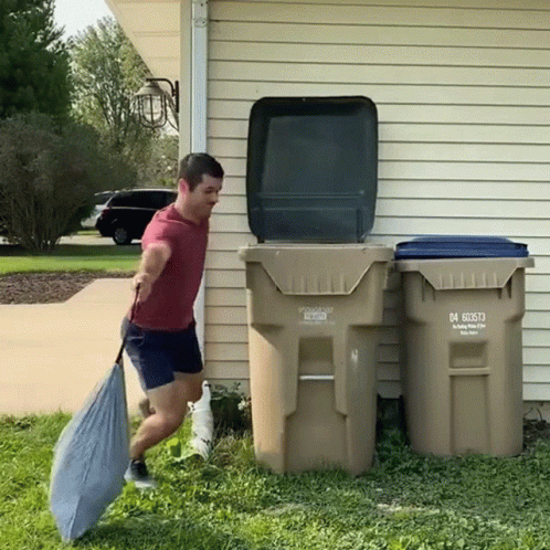A Man Is Carrying A Bag In Front Of A Garbage Can That Says 04 60573 GIF