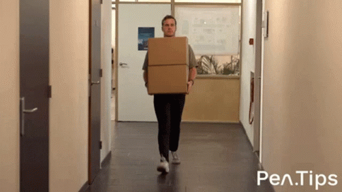 a man is carrying a cardboard box down a hallway with pen tips written on the bottom of the image