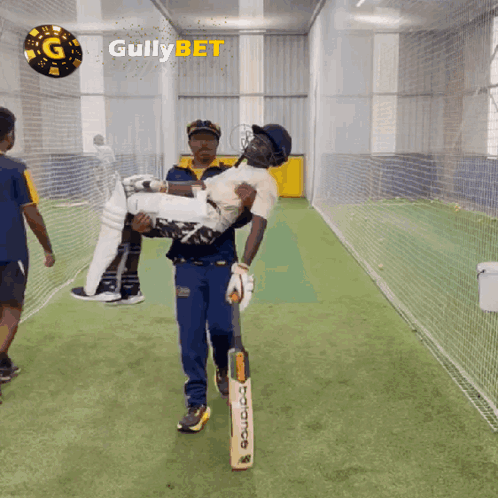 A Man Is Carrying A Cricket Player In His Arms With Gullybet Written On The Bottom GIF
