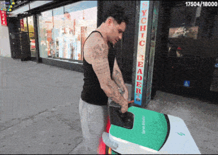 A Man Is Carrying A Green Surfboard In Front Of A Store Called Psychic Reader GIF