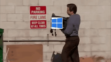 A Man Is Carrying A Laptop In Front Of A No Parking Fire Lane Sign GIF