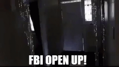 A Man Is Carrying A Large Box In A Hallway And The Words `` Fbi Open Up '' Are Written On The Screen . GIF