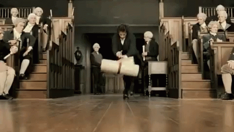 A Man Is Carrying A Large Piece Of Paper In Front Of A Group Of People Sitting In A Lecture Hall . GIF