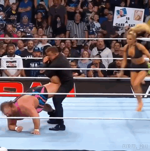 A Man Is Carrying A Woman In A Wrestling Ring With A Sign That Says Is A Cake Eat . GIF