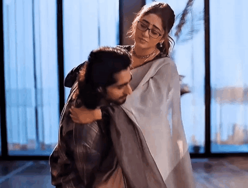 A Man Is Carrying A Woman In His Arms In A Room . GIF