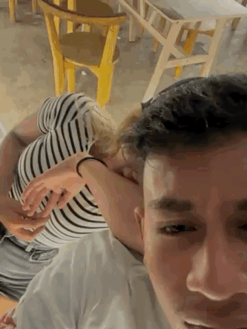 A Man Is Carrying A Woman On His Shoulders In A Room . GIF