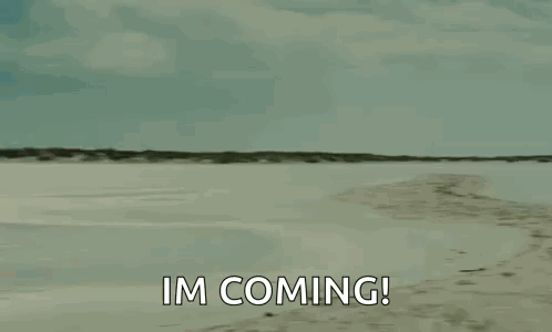 A Man Is Carrying A Woman On His Shoulders On A Beach And Saying `` Im Coming '' . GIF