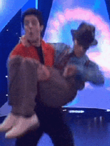 A Man Is Carrying Another Man In His Arms GIF