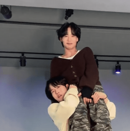 A Man Is Carrying Another Man On His Back On A Stage . GIF