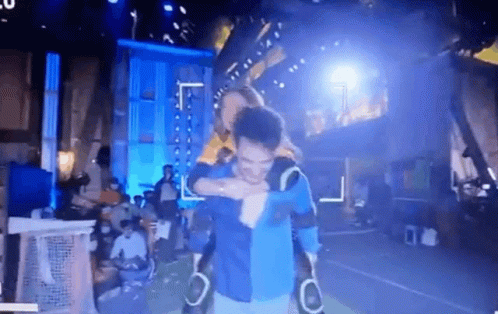 A Man Is Carrying Another Man On His Shoulders In A Dark Room . GIF