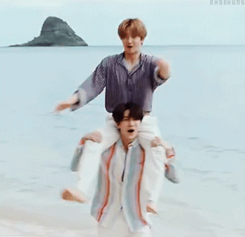 A Man Is Carrying Another Man On His Shoulders In The Water GIF