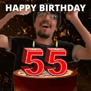 A Man Is Celebrating His 55Th Birthday By Blowing Out Candles On A Cake GIF