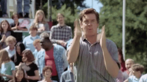 A Man Is Clapping His Hands In Front Of A Crowd . GIF