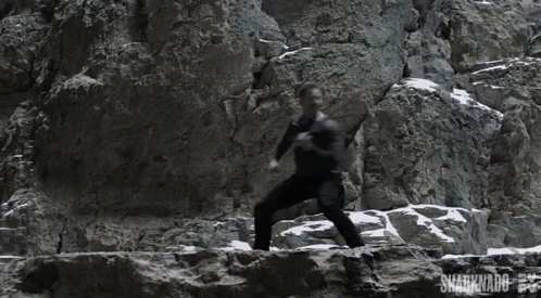 A Man Is Climbing A Rock Wall With The Words Sharknado On The Bottom Right GIF