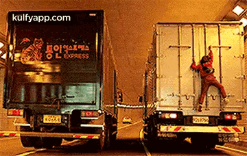 A Man Is Climbing On The Back Of A Semi Truck . GIF