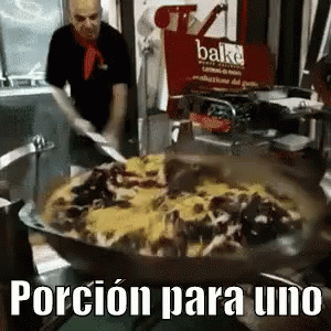 A Man Is Cooking Food In A Pan With The Words Porcion Para Uno In The Corner GIF