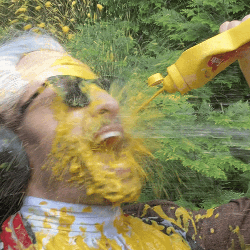 A Man Is Covered In Mustard While Holding A Bottle GIF