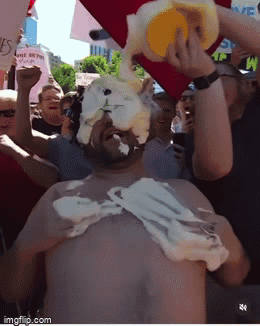 A Man Is Covered In Whipped Cream While Holding A Bucket In His Hand GIF
