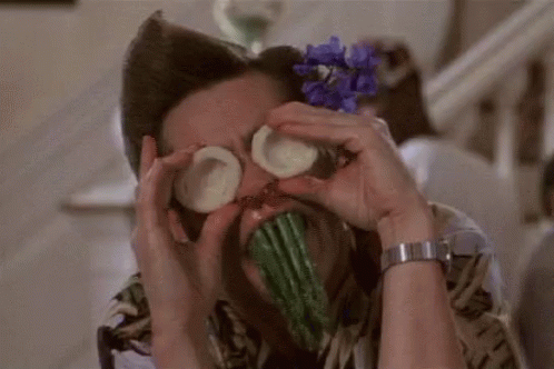 A Man Is Covering His Eyes With Cucumbers And Asparagus . GIF