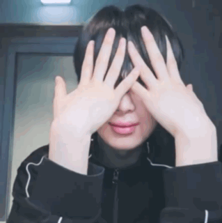 A Man Is Covering His Eyes With His Hands . GIF