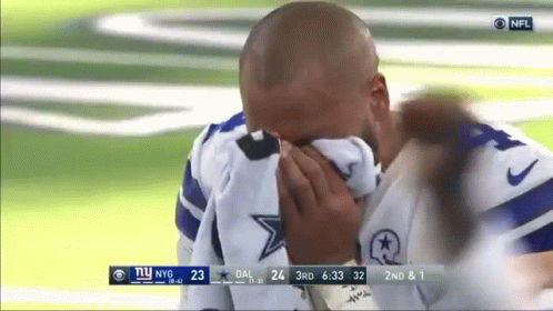 A Man Is Covering His Face With A Towel While Watching A Football Game . GIF