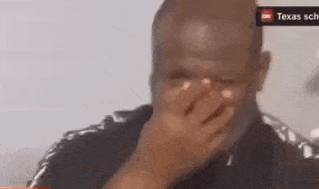 A Man Is Covering His Face With His Hand In Front Of A Sign That Says Texas GIF
