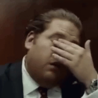 A Man Is Covering His Face With His Hand . GIF