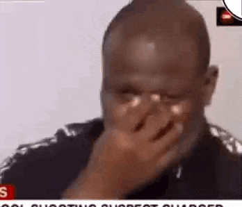 A Man Is Covering His Face With His Hand While Crying . GIF