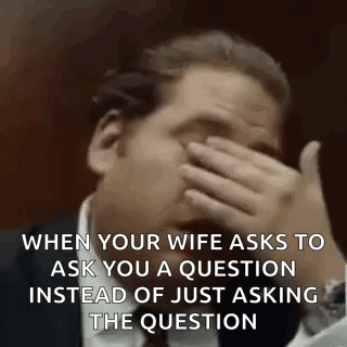 A Man Is Covering His Face With His Hand While Talking To His Wife . GIF