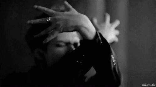 A Man Is Covering His Face With His Hands In A Black And White Photo . GIF