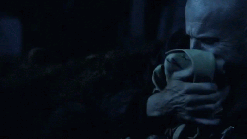 a man is covering his mouth with a napkin in the dark .
