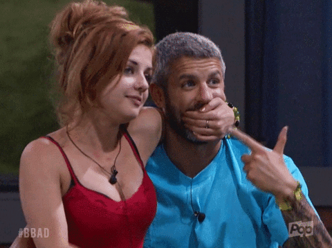 a man is covering his mouth with his hand and a woman is pointing at him