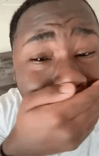A Man Is Covering His Mouth With His Hand While Laughing . GIF