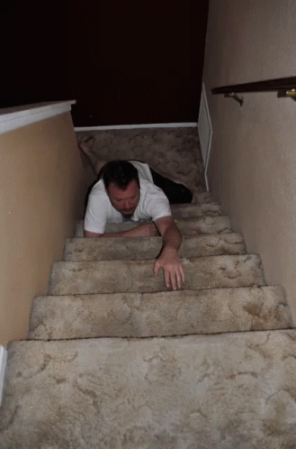 A Man Is Crawling Up A Set Of Stairs With His Legs Crossed GIF