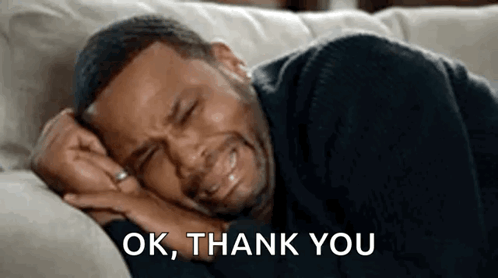 A Man Is Crying While Laying On A Couch . GIF