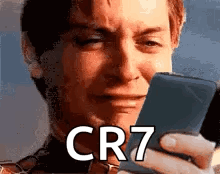 A Man Is Crying While Looking At A Cell Phone With The Word Cr7 On It . GIF