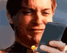 a man is crying while looking at his phone .