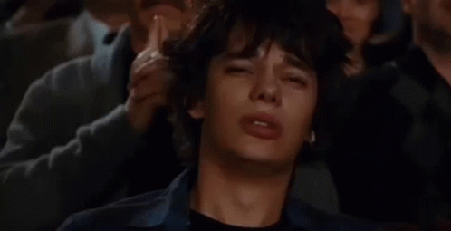 A Man Is Crying While Sitting In A Crowd Of People Watching A Movie . GIF