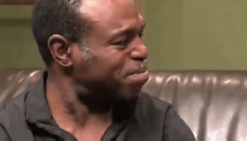 A Man Is Crying While Sitting On A Couch And Making A Funny Face . GIF