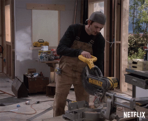 A Man Is Cutting A Piece Of Wood With A Dewalt Circular Saw GIF