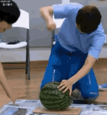 A Man Is Cutting A Watermelon With A Knife . GIF