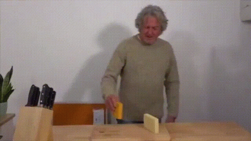 A Man Is Cutting Cheese On A Cutting Board GIF