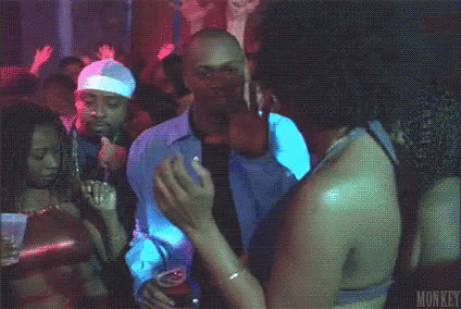 A Man Is Dancing In A Club While Holding A Drink . GIF