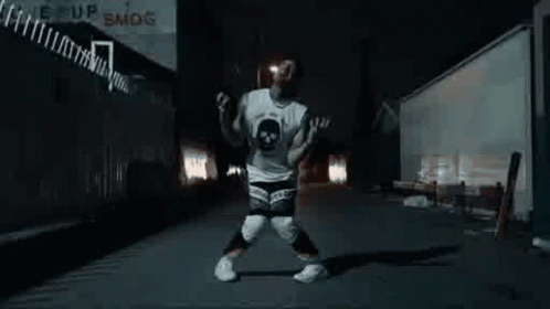 A Man Is Dancing In A Dark Alleyway At Night . GIF