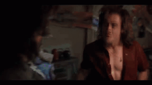 A Man Is Dancing In A Dark Room With His Arms Outstretched . GIF
