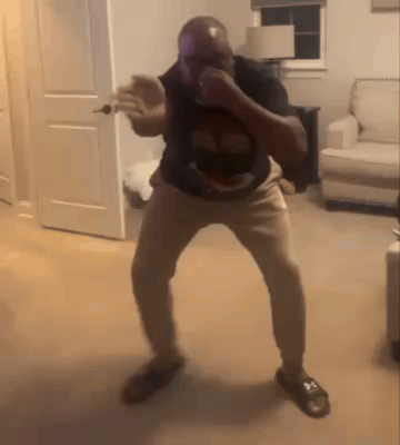 A Man Is Dancing In A Living Room In Front Of A Couch And A Door . GIF