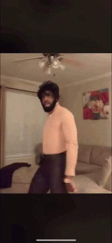 A Man Is Dancing In A Living Room With A Ceiling Fan GIF