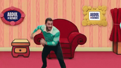 A Man Is Dancing In A Living Room With A Sign That Says Abdul The Senate On It GIF