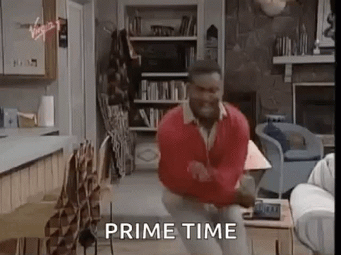 A Man Is Dancing In A Living Room With The Words `` Prime Time '' Written Above Him . GIF